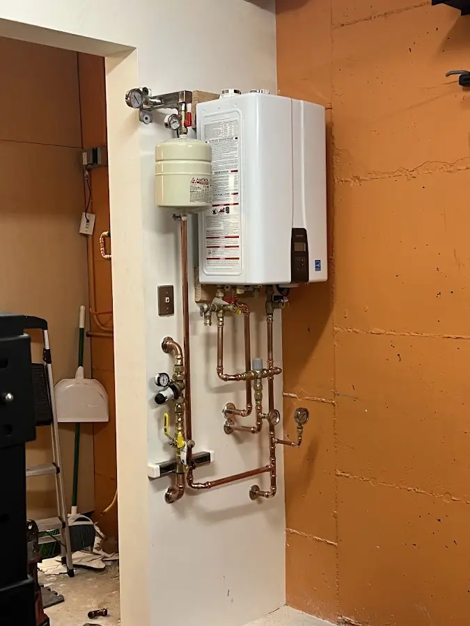 Plumbing technician inspecting water heater connections in Ball